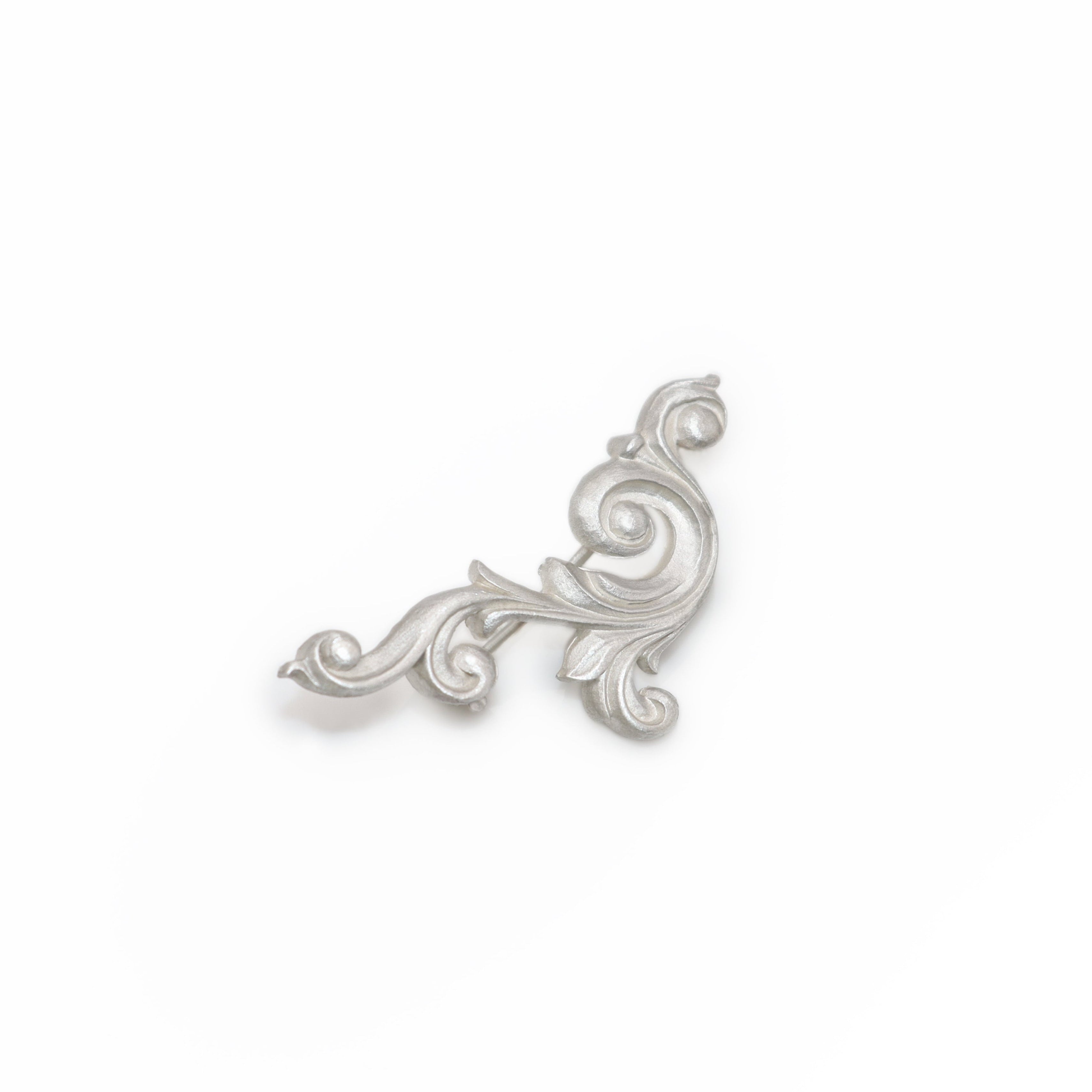Silver decorative scroll brooch on a white background